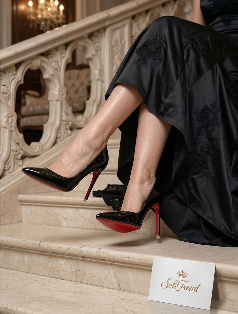 Puede incluir: Un par de zapatos de tac&oacute;n alto de charol negro con punta afilada y suelas de color rojo brillante. Los zapatos se llevan con un vestido largo negro con bordados florales. Se ve una tarjeta blanca con un icono de corona dorada y el texto Sole Trend.
