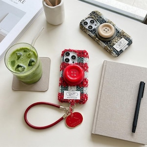 Elegante custodia per iPhone in tweed con pulsante di impugnatura e cinturino da polso di design.
