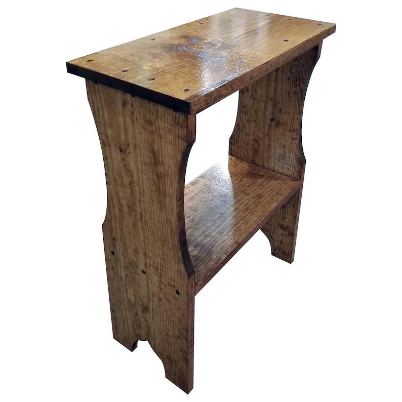 Pode incluir: Uma mesa de apoio alta e estreita em madeira com um acabamento brilhante em castanho m&eacute;dio. A pe&ccedil;a apresenta um tampo retangular, uma prateleira inferior &uacute;nica e dois pain&eacute;is laterais verticais com recortes curvos.