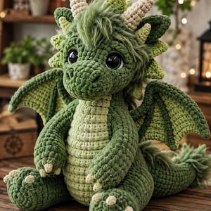 May include: A crocheted dragon plush toy featuring a dark green body with a lighter green belly, large dark eyes, and cream-colored horns. The creature has textured wings, a tuft of green fur on its head, and small claws on its feet and hands.