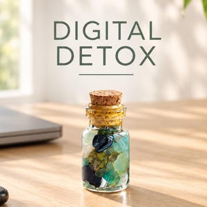 May include: A small clear glass bottle with a cork stopper filled with various polished blue, green, and white stones. The text DIGITAL DETOX is printed above the bottle, which sits on a wooden surface near a smartphone and a notebook.