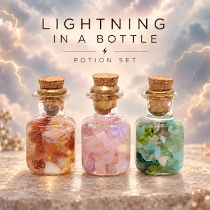 May include: Three small glass bottles with cork stoppers, each filled with colorful tumbled gemstones. The left bottle contains orange and red stones, the center contains pink stones, and the right contains green and blue stones. Text reads LIGHTNING IN A BOTTLE POTION SET.