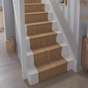 May include: A staircase featuring a natural brown woven fibre runner installed over white painted wooden steps. The runner covers the centre of each tread and riser, providing a textured contrast against the smooth white finish of the stairs.