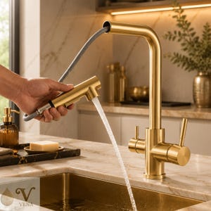 May include: A brushed gold kitchen faucet with a pull-down sprayer head and a flexible grey hose. The faucet features a high-arc spout, two side handles for water control, and a steady stream of water flowing from the sprayer into a gold sink.