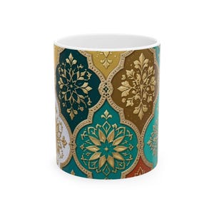 May include: A cylindrical ceramic mug featuring a repeating pattern of interlocking quatrefoil shapes. Each shape contains a gold-colored floral mandala design set against a background of teal, dark green, brown, orange, and white colors.