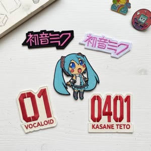 May include: A collection of embroidered patches featuring a teal-haired anime character, two text patches with Japanese characters, and two white patches with red numbers 01 and 0401, labeled VOCALOID and KASANE TETO, plus two small circular pins.