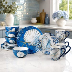 Puede incluir: Un juego de vajilla con temática costera en azul profundo y blanco, con ilustraciones de conchas marinas, estrellas de mar y corales. La colección incluye cuencos apilados, un plato grande, un plato pequeño y varias tazas con asa.