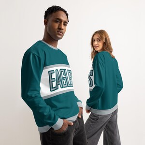 May include: Teal sweatshirt with the word "EAGLES" in white and grey block letters across the chest. The sweatshirt has a grey collar and cuffs. The image shows the front and back of the sweatshirt.