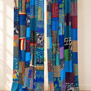 Könnte beinhalten: Ein Paar bodenlange Vorhänge mit einem lebendigen Patchwork-Design, das aus verschiedenen rechteckigen Stoffbahnen besteht. Die Textilien zeigen eine vielfältige Auswahl an blauen, grünen, roten und goldenen Mustern, darunter florale und geometrische Motive.