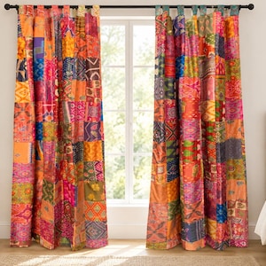 Puede incluir: Dos cortinas de piso a techo con un vibrante diseño de patchwork hecho de varios cuadrados de tela en tonos naranja, rosa, amarillo, azul y verde. Las cortinas cuelgan de una barra negra mediante trabillas de tela y muestran diversos patrones.