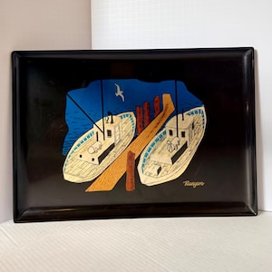 May include: A rectangular black serving tray featuring a graphic illustration of two white boats docked at a wooden pier. The scene includes a deep blue water background, a small white bird in the sky, and the signature Runyan printed in white.