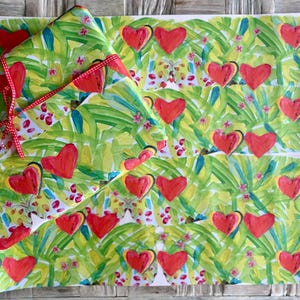 May include: Gift wrap featuring a repeating pattern of red hearts on a green and yellow background with a tropical leaf design. A wrapped gift is tied with a red ribbon. The overall theme is love and romance.