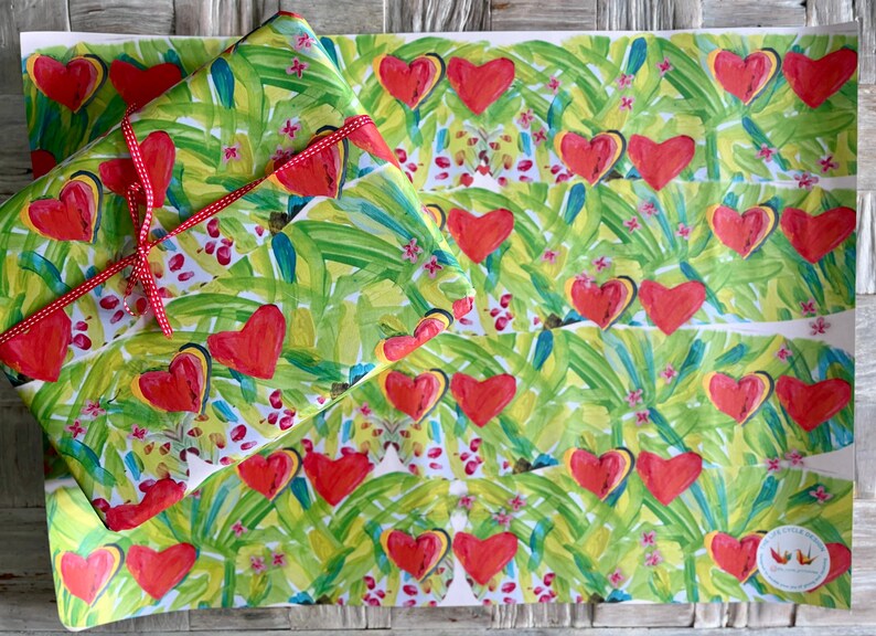 May include: Gift wrap featuring a repeating pattern of red hearts on a green and yellow background with a tropical leaf design. A wrapped gift is tied with a red ribbon. The overall theme is love and romance.