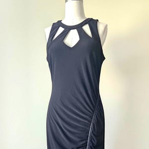 May include: A black sleeveless dress with a keyhole neckline and a side split. The dress has a ruched detail with a zip. The dress is displayed on a mannequin.