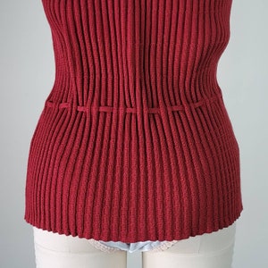 May include: A red ribbed knit top with a cinched waist. The top is made of a soft, stretchy material and has a relaxed fit.