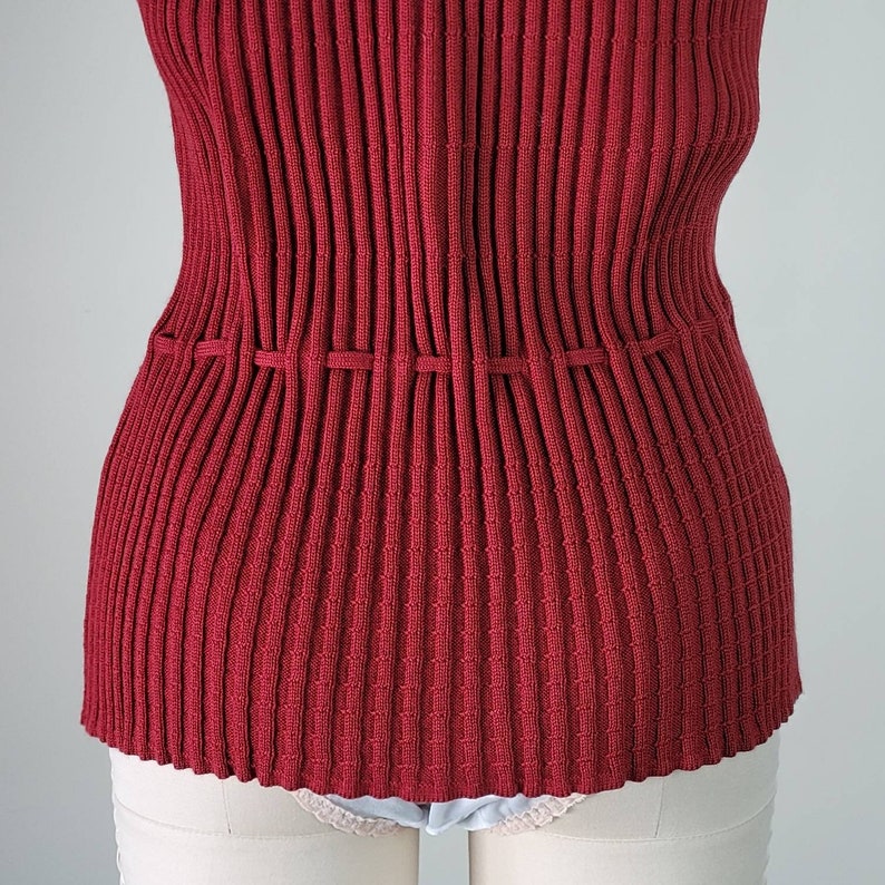 May include: A red ribbed knit top with a cinched waist. The top is made of a soft, stretchy material and has a relaxed fit.