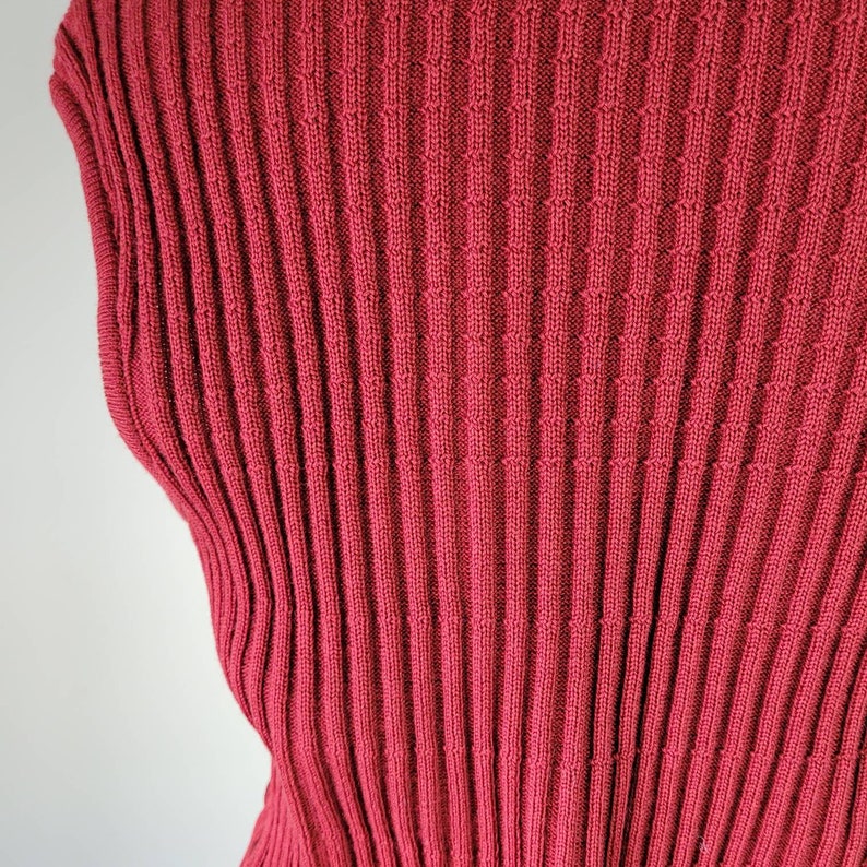 May include: A close-up of a red ribbed knit fabric. The fabric has a fine knit and a smooth texture.