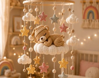 Pode incluir: Um móbile suspenso para quarto de bebé com um urso central de croché castanho a dormir numa nuvem branca. O móbile inclui vários elementos de croché suspensos num aro de madeira, incluindo nuvens brancas, estrelas amarelas, rosas e azuis.