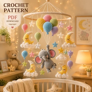 May include: A crochet pattern PDF download for a nursery mobile featuring a central gray elephant, yellow crescent moons on white clouds, colorful balloons, and small stars. The mobile is suspended from a circular frame with white strings.