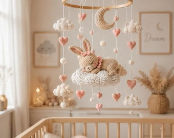Pode incluir: Um móbile suspenso para quarto de bebé com moldura circular de madeira, nuvens de croché brancas, corações de croché cor-de-rosa, pequenos pompons brancos, uma lua crescente bege e um coelho de croché bege a dormir numa nuvem branca.