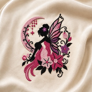 Könnte beinhalten: Ein Stickmotiv mit der schwarzen Silhouette einer Fee mit Flügeln, die auf einem rosafarbenen Halbmond sitzt. Die Fee trägt ein rosafarbenes Kleid und ist von rosa und violetten Blumen, schwarzen Ranken und hängenden Perlen umgeben.