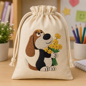 Könnte beinhalten: Ein cremefarbener Stoffbeutel mit Kordelzug, der mit einem gestickten braun-schwarz-weißen Hund verziert ist, welcher einen Strauß gelber Blumen mit grünen Stielen hält. Der Beutel hat einen gerafften Verschluss mit zwei dicken, cremefarbenen Kordeln.