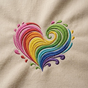 Könnte beinhalten: Ein beigefarbener Stoff mit einem zentralen, gestickten Herzmotiv. Das Herz besteht aus geschwungenen, wirbelnden Linien in einem lebendigen Regenbogenspektrum, das von Pink und Rot über Orange, Gelb, Grün und Blau bis hin zu Violett reicht.