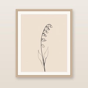 以下が含まれることがあります： ベージュの無地背景にスズランの花を黒い線画で描いた額装アートプリント。作品は明るい茶色の木製フレームに収められており、複数の小さなベル型の花がついた一本の茎が描かれています。