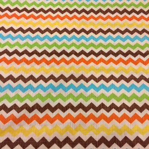 May include: A colorful fabric with a repeating chevron pattern. The zigzags alternate between brown, orange, yellow, green, blue, and white. A ruler is at the bottom of the image, showing measurements in inches.