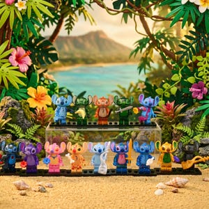 May include: A collection of colorful Stitch character figurines displayed on a sandy beach setting with tropical foliage and a scenic backdrop. Each figurine is uniquely designed, holding various accessories.