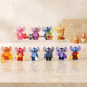 May include: A collection of eleven colorful Stitch character figurines, each with unique accessories. The figurines are in various poses and colors, including pink, blue, and orange. Some hold items like ice cream cones and guitars.