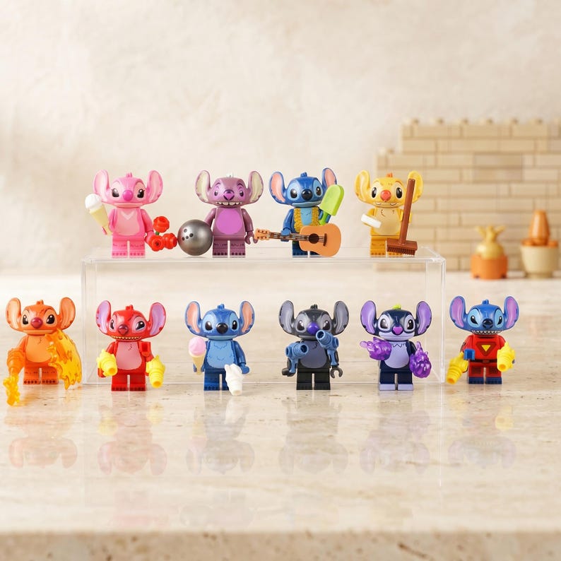 May include: A collection of eleven colorful Stitch character figurines, each with unique accessories. The figurines are in various poses and colors, including pink, blue, and orange. Some hold items like ice cream cones and guitars.
