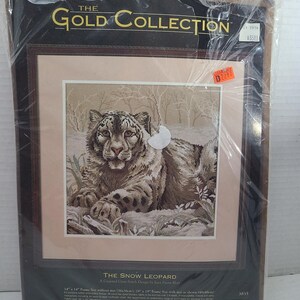 Puede incluir: Un kit de punto de cruz contado sellado titulado The Snow Leopard de The Gold Collection por Dimensions. El empaque presenta una imagen impresa de un leopardo de las nieves en un paisaje nevado, con texto que indica un tamaño de marco de 36cm.