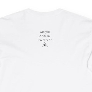 Op de afbeelding: Een effen wit shirt met lange mouwen en zwarte tekst in het midden op de bovenrug die luidt can you SEE the TRUTH? boven een kleine zwarte lijntekening van een driehoek met een oogsymbool. De stof is glad en volledig wit van kleur.