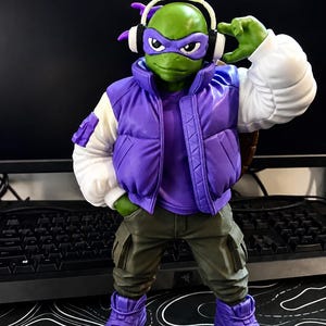 May include: A Teenage Mutant Ninja Turtle action figure wearing a purple puffer vest over a purple t-shirt, white sleeves, olive green cargo pants, and purple high-top sneakers. The figure wears a purple eye mask and white over-ear headphones.
