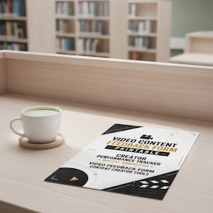 Könnte beinhalten: Eine weiße Keramiktasse auf einem Holzuntersetzer neben einem ausgedruckten Dokument mit dem Titel Video Content Feedback Form Printable. Das Dokument enthält schwarze und goldene Grafikelemente, darunter ein Filmklappen-Symbol und Text für einen Creator Performance Tracker.
