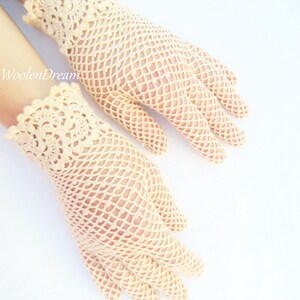 May include: A pair of cream-coloured crocheted gloves with a delicate lace pattern at the wrist.
