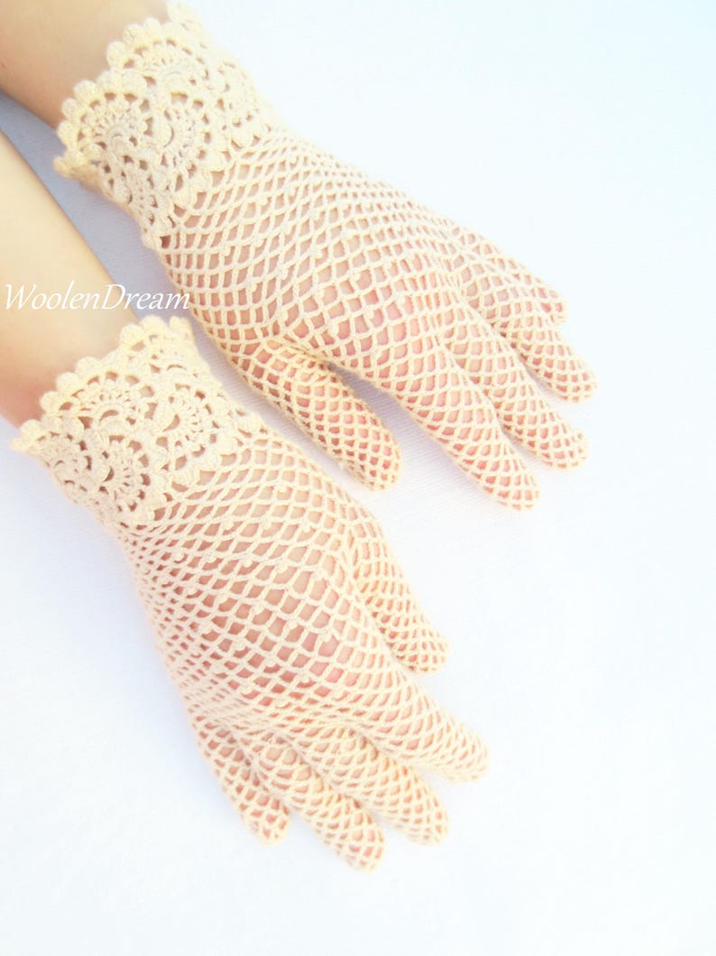 May include: A pair of cream-coloured crocheted gloves with a delicate lace pattern at the wrist.