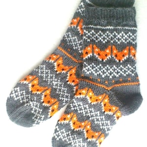 May include: A pair of gray, white, and orange knitted socks with a fox pattern.