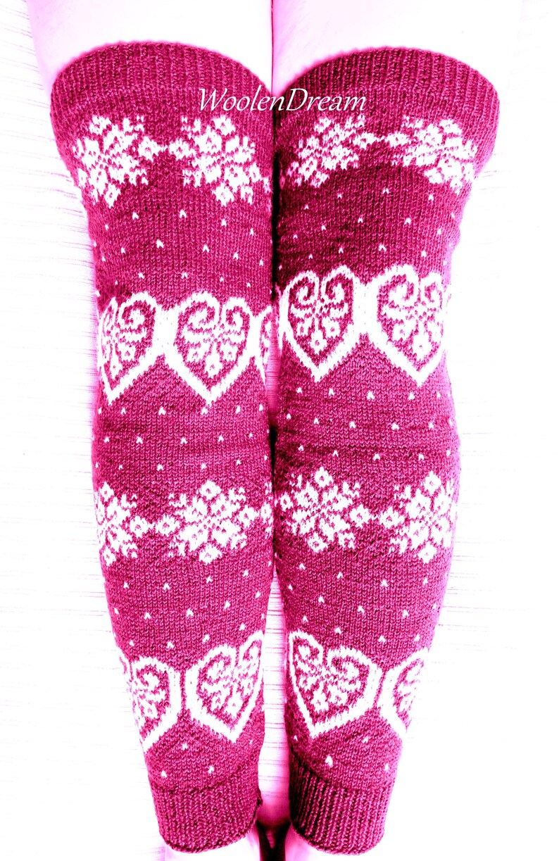 May include: Burgundy knee-high leg warmers with white snowflake and heart patterns. The knitted leg warmers have a ribbed cuff and are adorned with the text "WoolenDream". These warmers are perfect for winter wear.