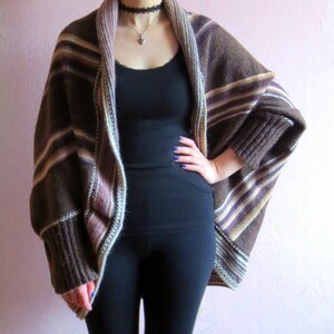 May include: A brown and white striped cardigan with long sleeves and a draped front. The cardigan is made of a soft, knitted fabric.