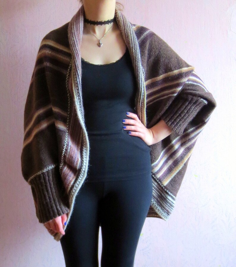 May include: A brown and white striped cardigan with long sleeves and a draped front. The cardigan is made of a soft, knitted fabric.