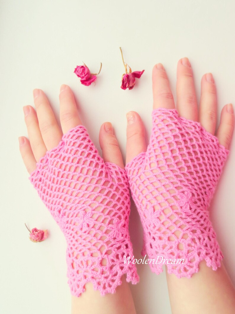 May include: A pair of pink crocheted fingerless gloves with a delicate lace trim. The gloves are made with a fine, open-weave pattern.