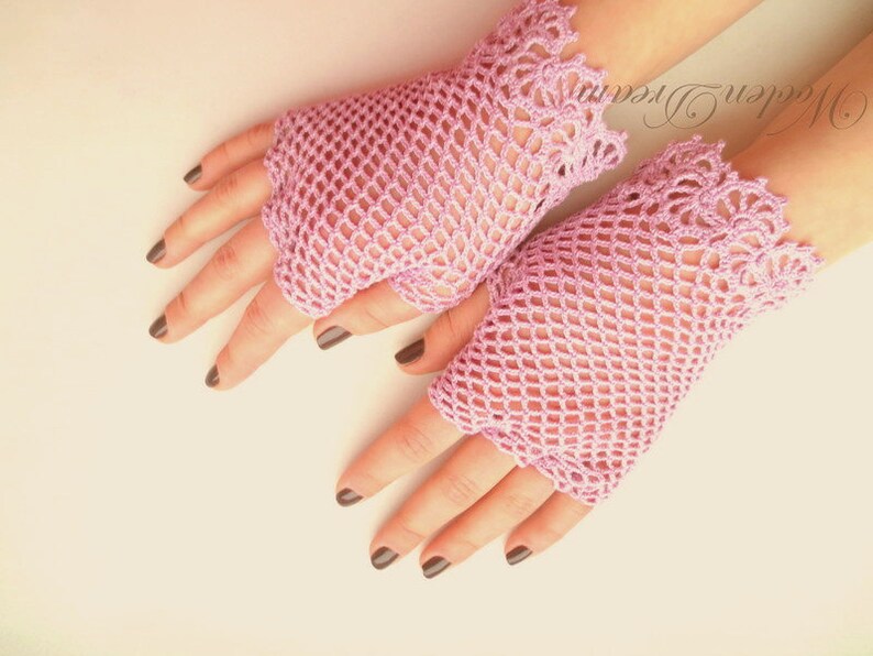 May include: A pair of pink crocheted fingerless gloves with a delicate lace trim. The gloves are made with a fine mesh pattern.