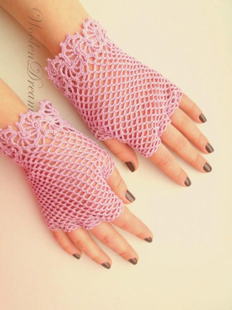 May include: A pair of pink crocheted fingerless gloves with a delicate lace pattern. The gloves are made with a fine yarn and have a loose, airy feel.