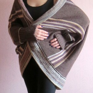 May include: A brown and white striped knit cardigan with a long, flowing design. The cardigan is open at the front and has a V-neck.