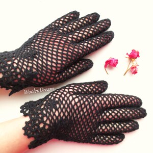 Puede incluir: Un par de guantes de ganchillo negros con un delicado patr&oacute;n de encaje. Los guantes est&aacute;n hechos de un material de malla fina y tienen un estilo ajustado.