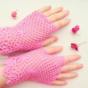 May include: A pair of pink crocheted fingerless gloves with a delicate lace pattern. The gloves are made of a lightweight, breathable material and are perfect for adding a touch of femininity to any outfit.