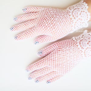 May include: A pair of white lace gloves with a delicate net pattern. The gloves have a scalloped edge and are made of a soft, lightweight fabric.