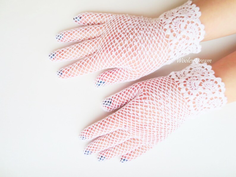 May include: A pair of white lace gloves with a delicate net pattern. The gloves have a scalloped edge and are made of a soft, lightweight fabric.